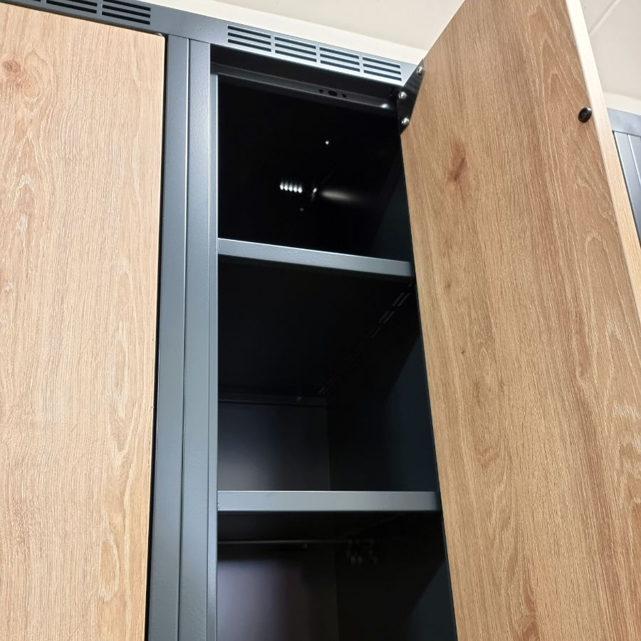 View of an open metal garment locker with storage shelves and a clothes hanging rail.