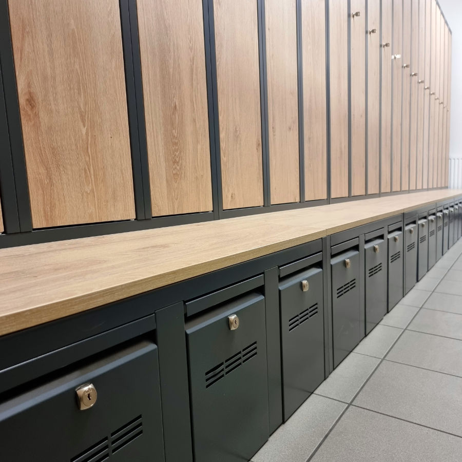 View of garment lockers placed on benches with pull-out shoe drawers.